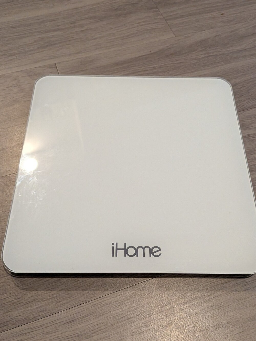 iHome digital bathroom scale featuring a sleek white tempered glass platform and